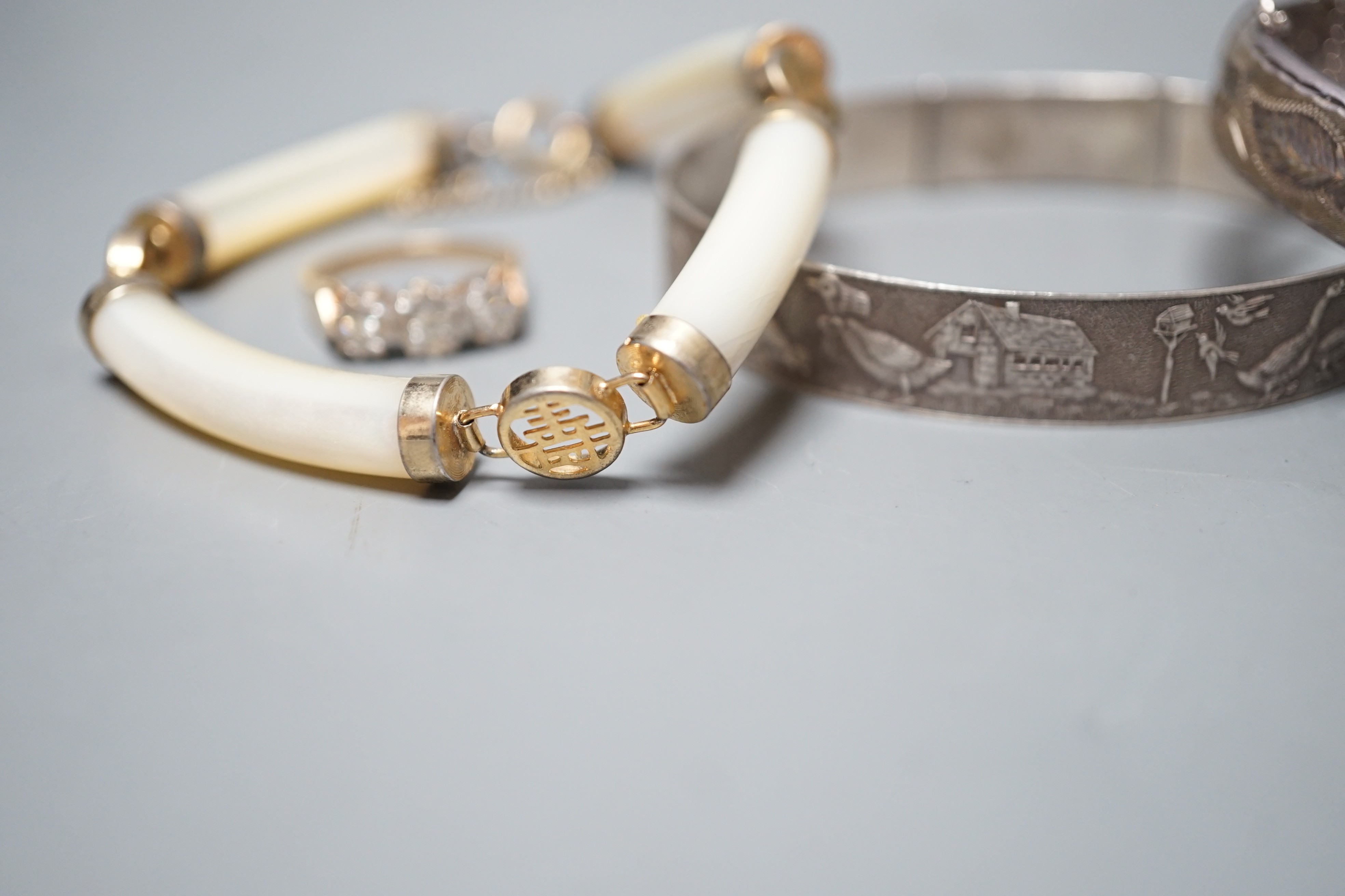 A modern 9ct gold and illusion set three stone diamond ring, size N/O, a Chinese gilt metal and mother of pearl bracelet and two white metal bangles, one hallmarked silver.